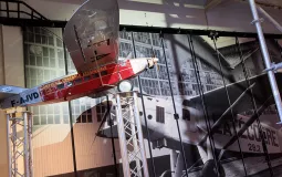 Au premier plan : une maquette d'un avion F-AJVD de la Compagnie Générale Aéropostale. À l'arrière-plan : une photo d'époque d'un avion Latécoère 28.2 devant les hangars de l'usine.