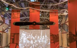 Une hélice d'un avion Laté 28 suspendue au-dessus d'une animation sur le travail dans les usines Latécoère réalisée avec des images d'époque