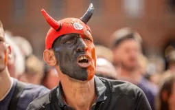 Un spectateur grimé en diable rouge et noir assiste à la diffusion en direct du match