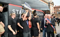 Des joueurs du Stade Toulousain brandissent le trophée de la Champions Cup place du Capitole, aux côtés de Jean-Luc Moudenc, après être descendus du bus