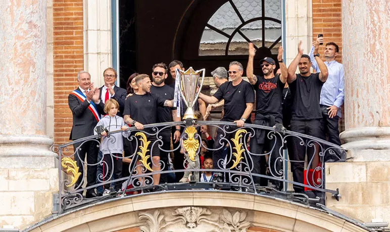 Des joueurs du Stade Toulousain brandissent le trophée de la Champions Cup depuis le balcon du Capitole